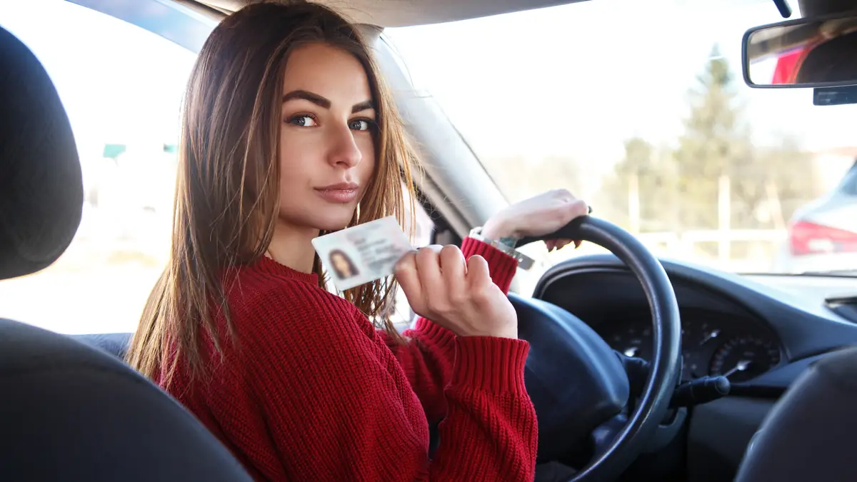 Führerschein zurück ohne MPU: Frau am Steuer hält lächelnd einen Führerschein hoch