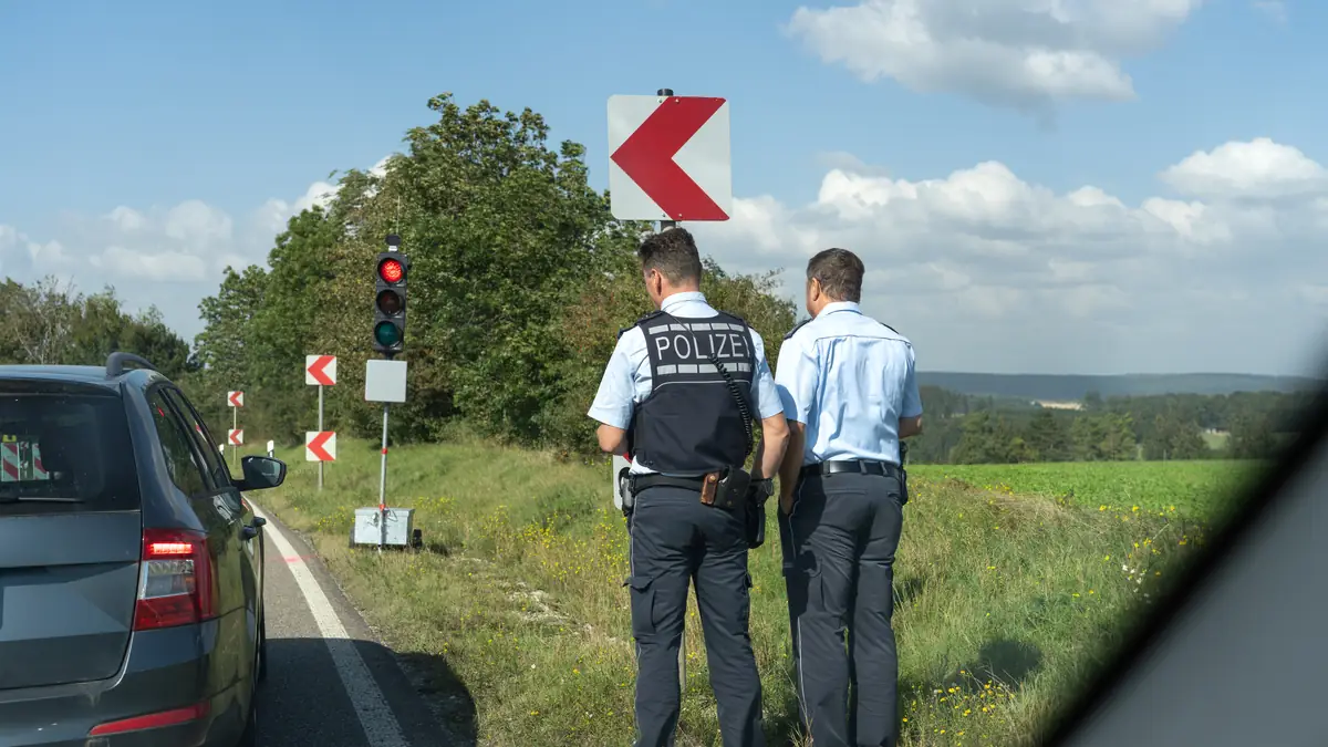 Wann wird eine MPU angeordnet: zwei Polizisten bei einer Verkehrskontrolle am Straßenrand, ein Auto hält